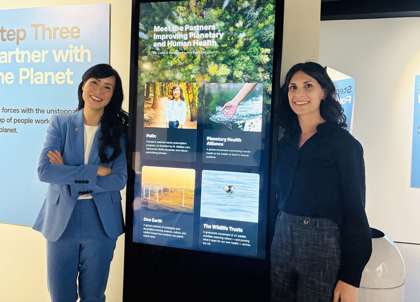 Dr. Melissa Lem and Dr. Rachel Marcus on either side of a tall interactive touch screen